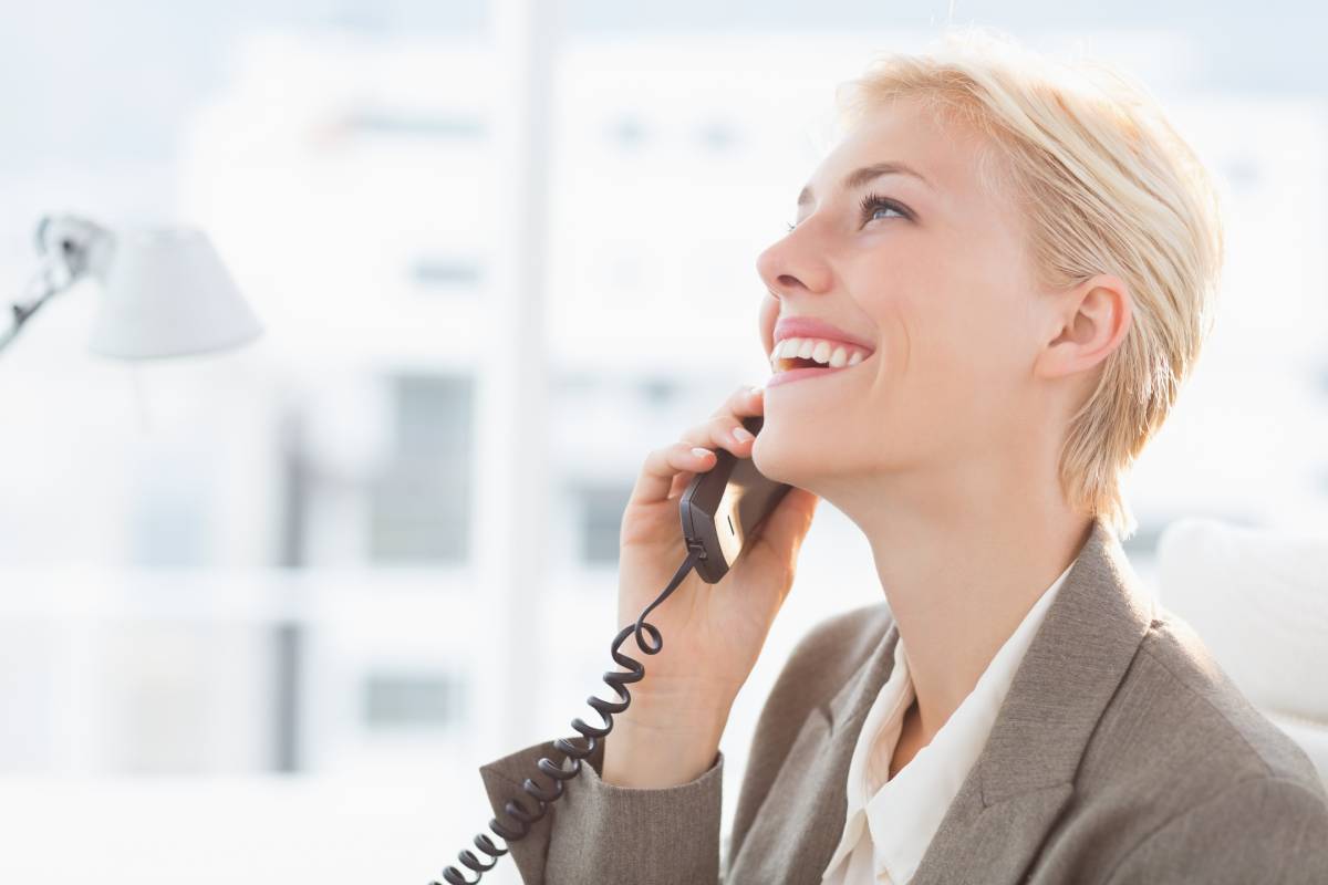 Woman with short blond hair talking and smiling while on the phone