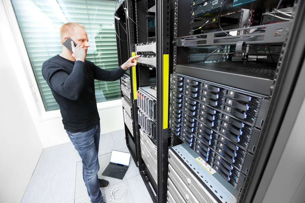 A service tech working in a server room and talking on the phone