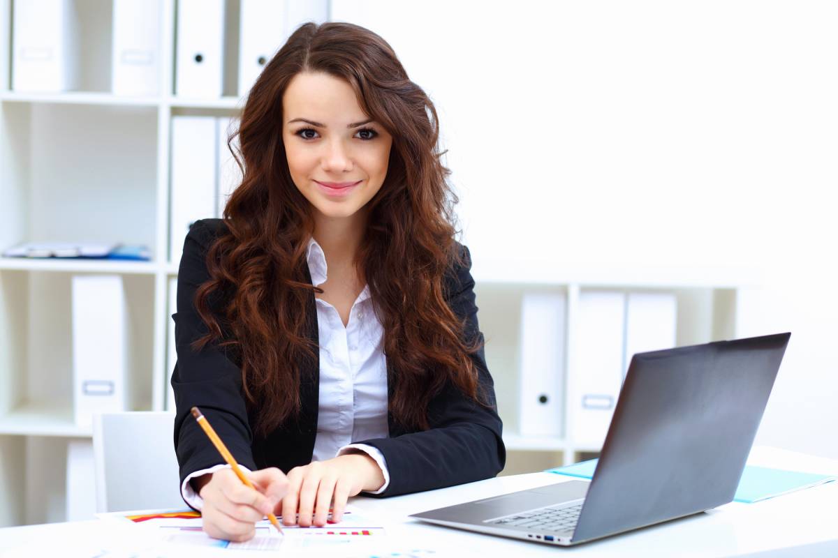 A woman smiling while working on a laptop