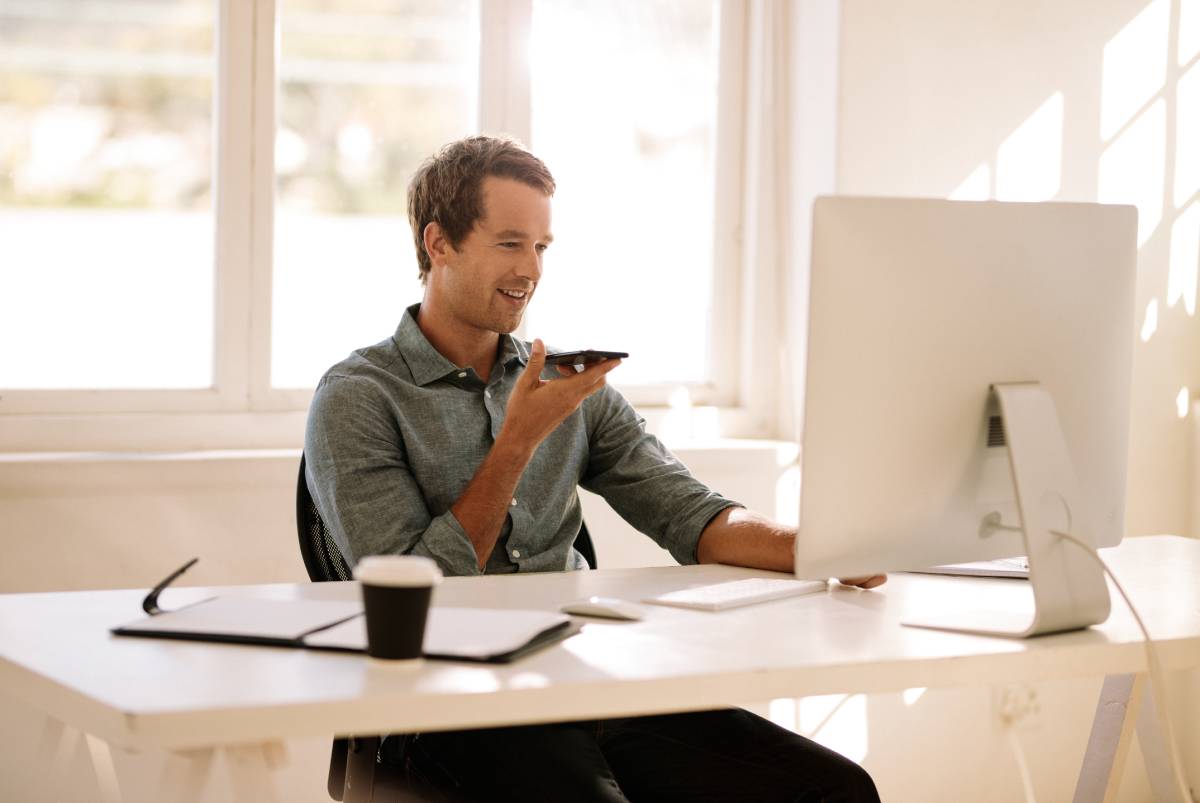 A man working from home working on his computer and talking on the phone