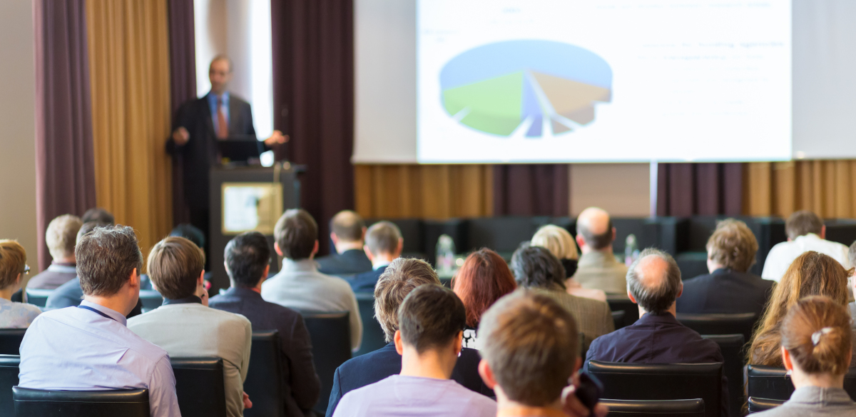 A man giving a presentation to a group of people at a convention