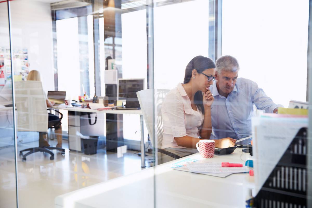 Man and woman sitting at a desk looking at a desktop computer