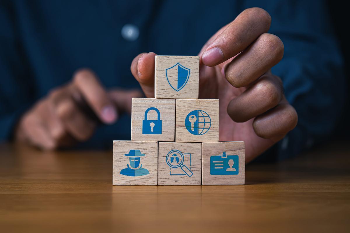 Person stacking wooden blocks printed with shield, lock, and security icons